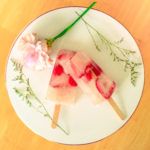 Beautiful blush pink Fruity Rosé Popsicles arranged on a white cake stand with floral garnish